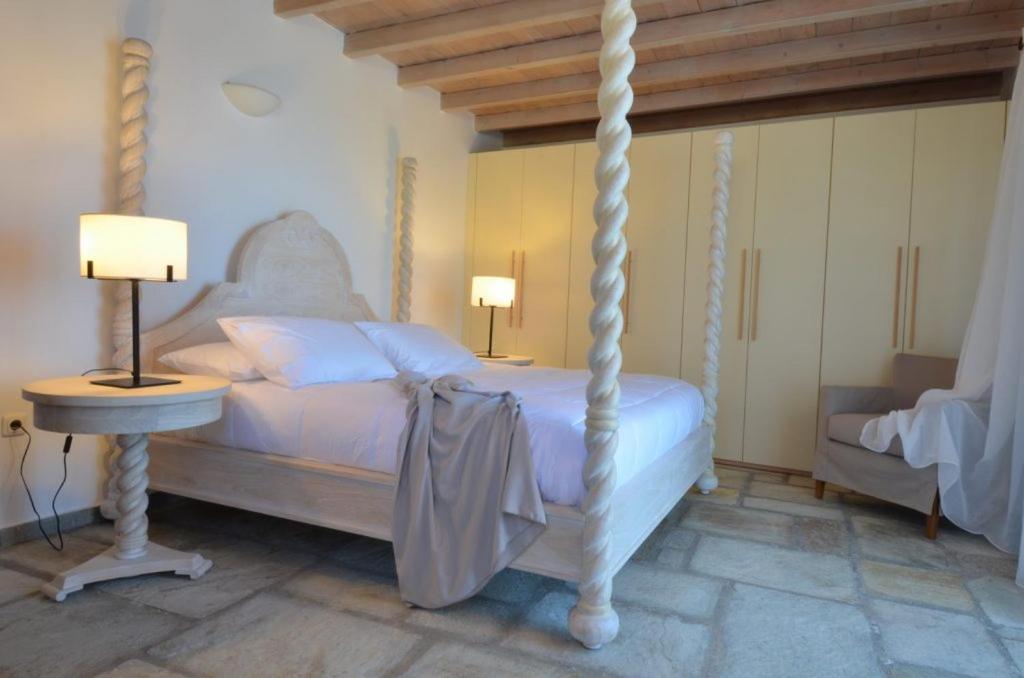 a bedroom with a white bed and a table and lamp at Aegea Blue Cycladic Resort in Zorgos 