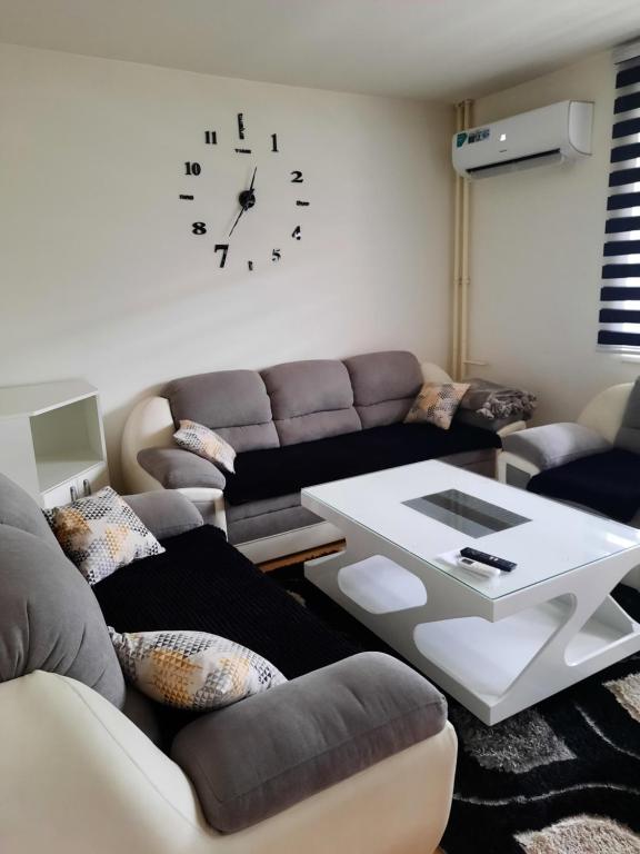 un soggiorno con divano e orologio sul muro di Apartman Marina a Foča