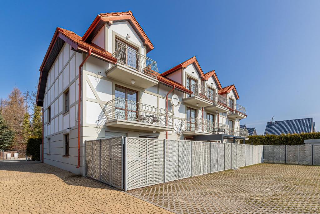 a building with a fence in front of it at Liliowa Seaside Apartments by Renters in Dębki