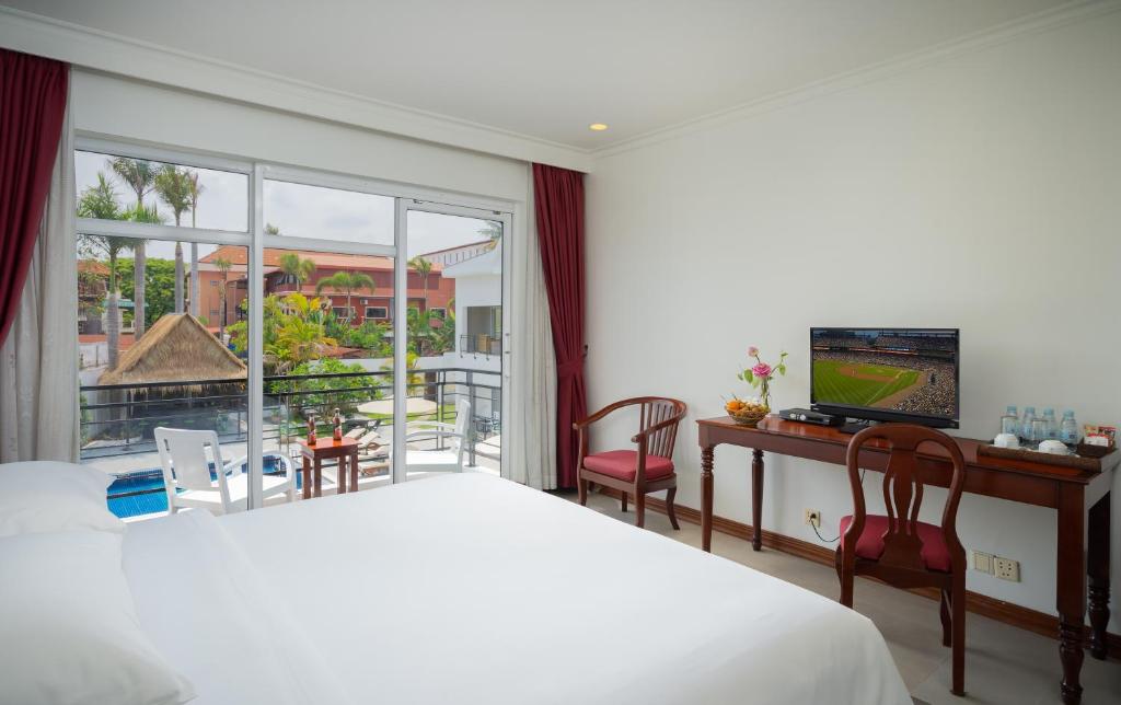 a bedroom with a bed and a television and a balcony at Sala Siem Reap Hotel in Siem Reap