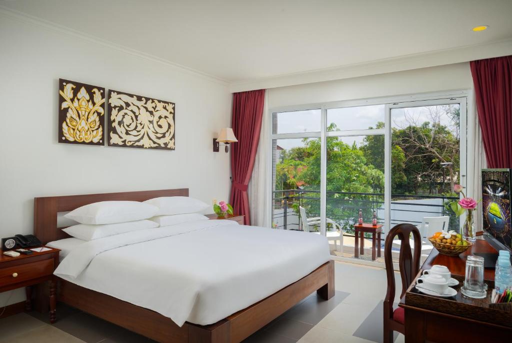 a hotel room with a bed and a balcony at Sala Siem Reap Hotel in Siem Reap