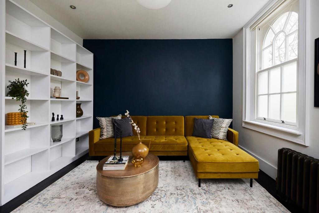 a living room with a yellow couch and a blue wall at The Southwark Townhouse - Adorable 3BDR House with Garden in London
