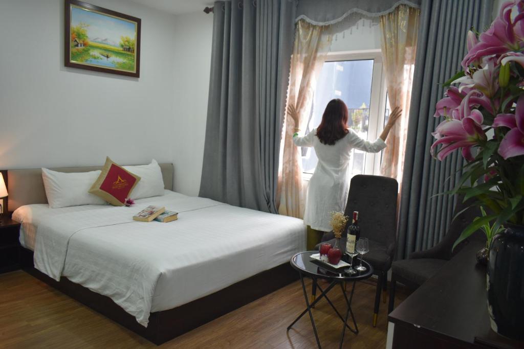 a woman is looking out the window of a hotel room at Hanoi Aria Central Hotel & Spa in Hanoi