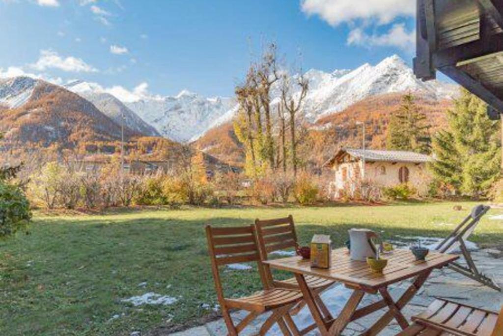 uma mesa de madeira e cadeiras num relvado com montanhas em Cocoon with garden and beautiful mountain view em Le Monêtier-les-Bains