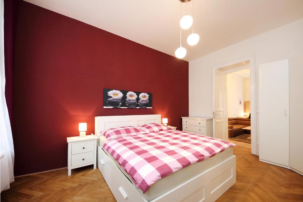 プラハにあるヒストリック センター アパートメンツ Vの赤いアクセントの壁のベッドルーム1室、ベッド1台が備わります。