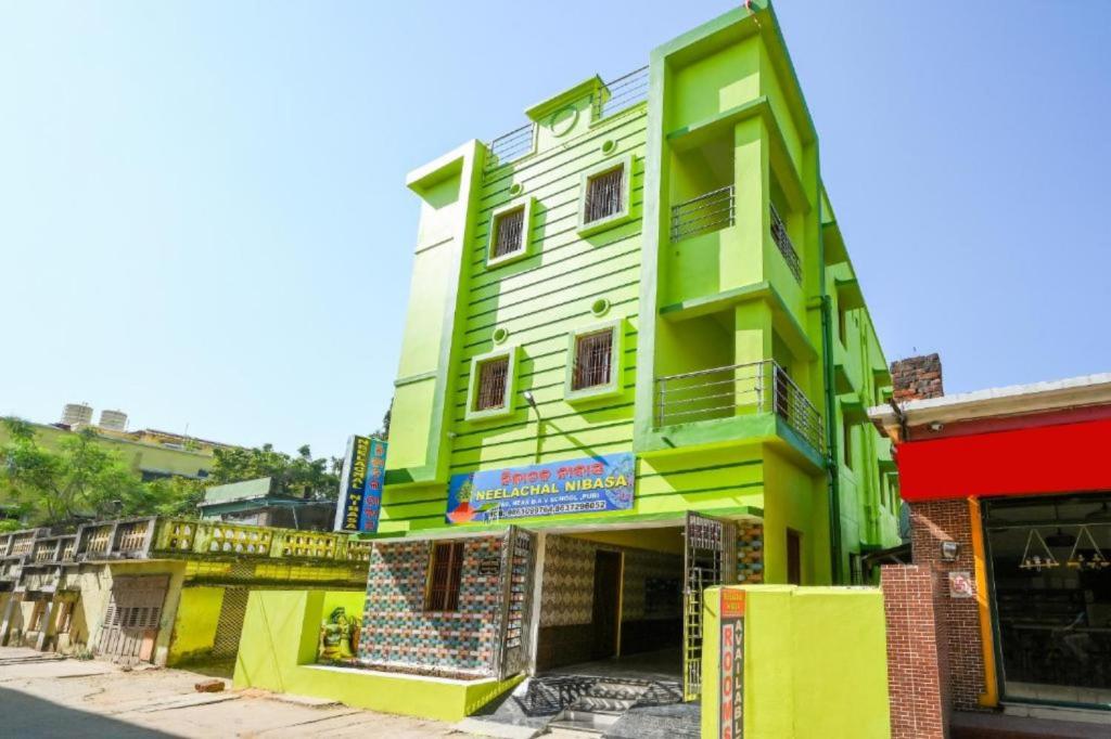 a green and white building on the side of a street at Goroomgo Neelachal Holiday Nibasa Puri in Puri