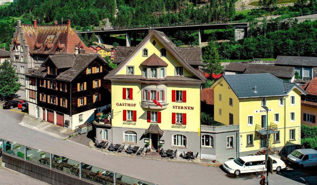 a yellow building with red windows in a town at Hotel Sternen in Gurtnellen