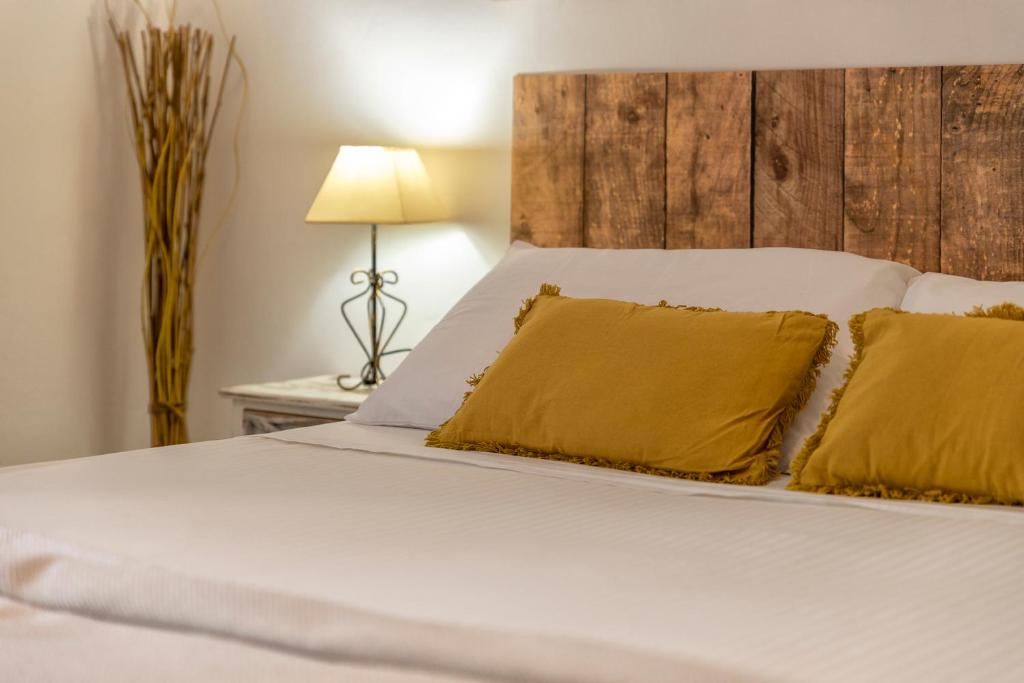un letto con lenzuola bianche e cuscini gialli di Affittacamere da Marianna ad Alghero