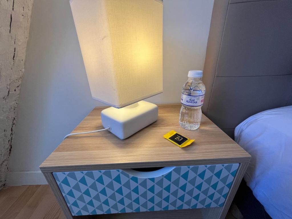 a desk with a bottle of water on a bed at Le Briais in Melun