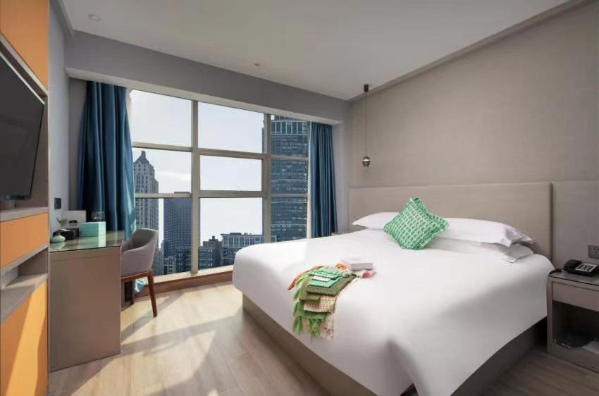 a bedroom with a large white bed and a large window at Yiwu Manting Hotel International Trade City义乌漫庭酒店 in Yiwu
