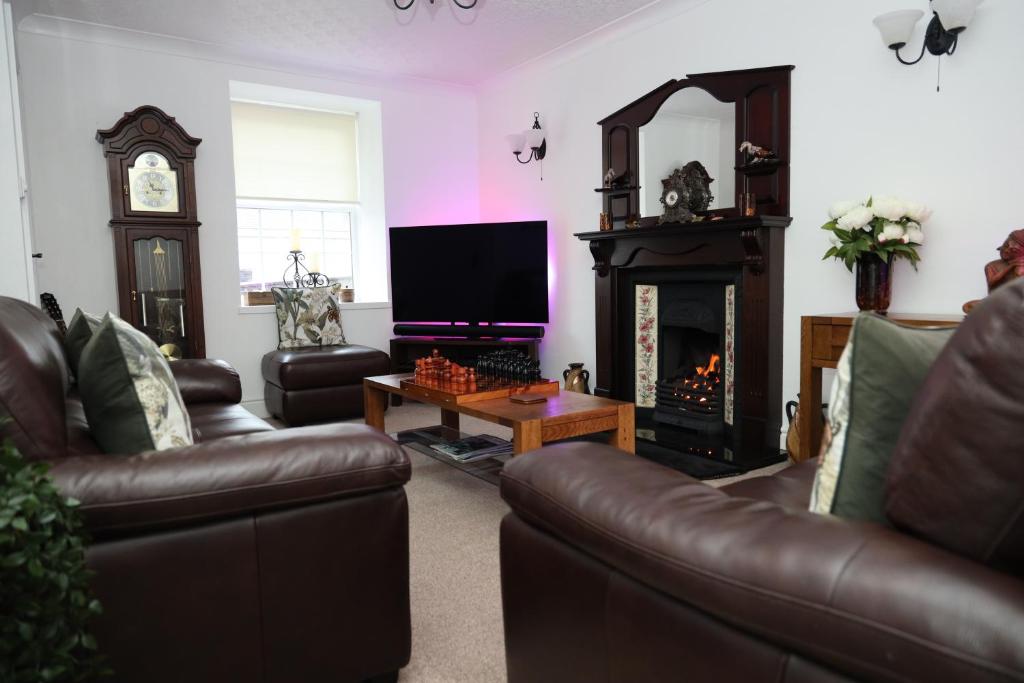 a living room with leather furniture and a fireplace at Bryn Derwen in Caernarfon