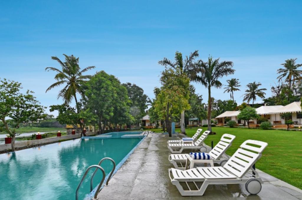 a group of white chairs next to a swimming pool at Shree Vilas Orchid - A Pichola Lake Facing Resort in Udaipur