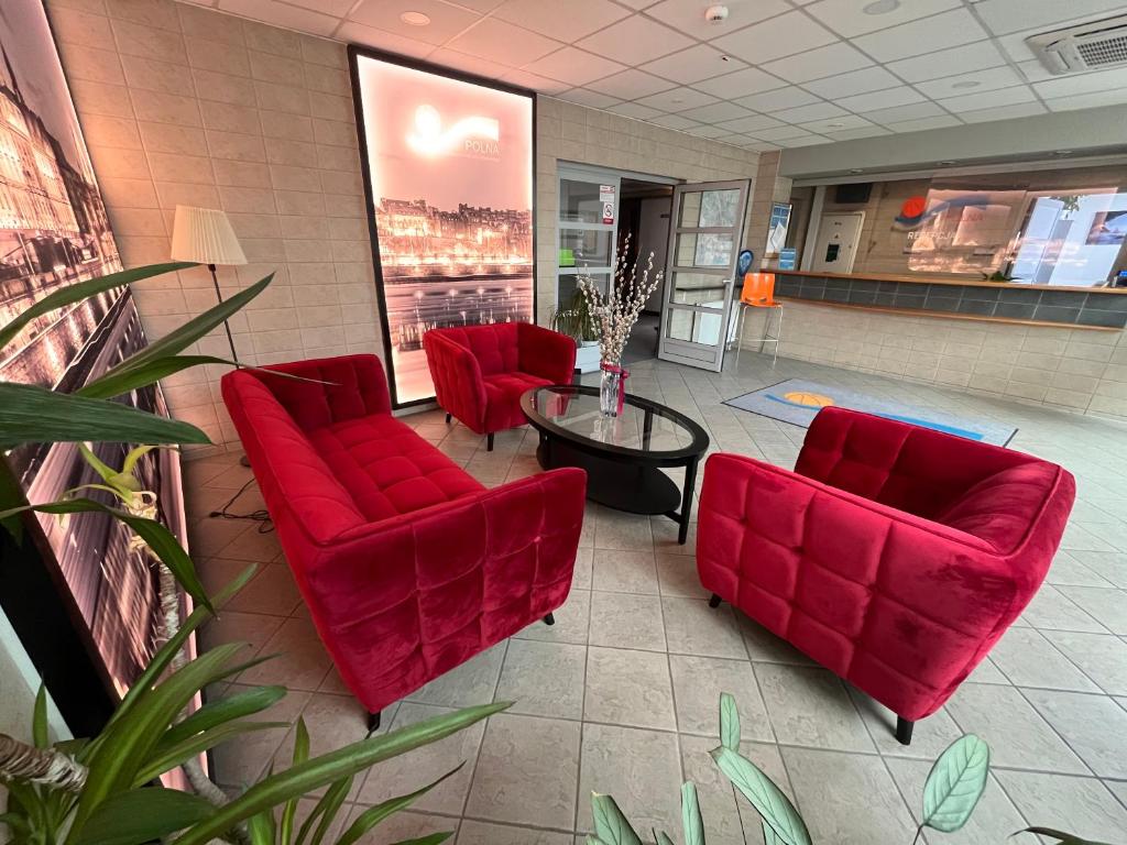 una sala de espera con sillas rojas y una mesa en OSiR Polna, en Varsovia