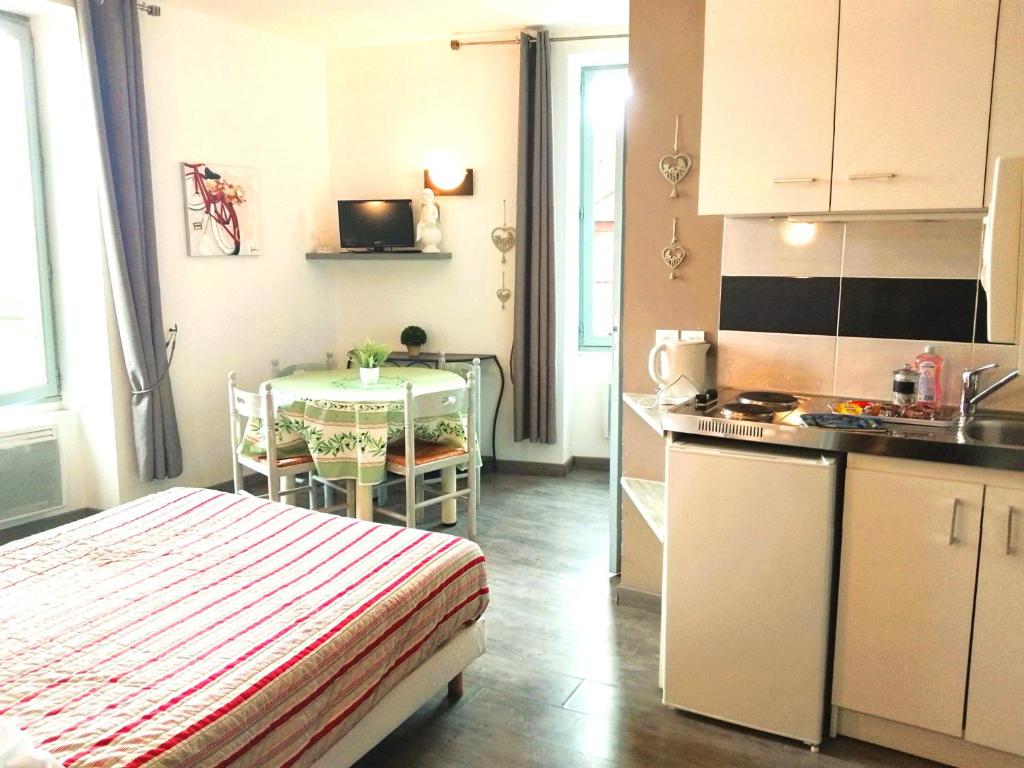 a room with a kitchen and a table with a bed at Le Relais Bastide de Cordes sur Ciel in Cordes-sur-Ciel