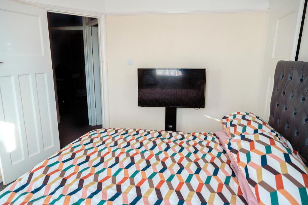 a bedroom with a bed and a flat screen tv at Exclusive 26 room in Ilford