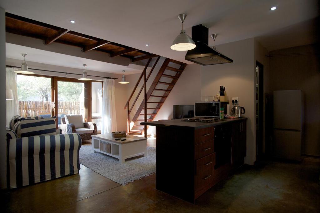 a living room with a kitchen and a living room with a staircase at Raptors Wildlife Escapes in Hoedspruit