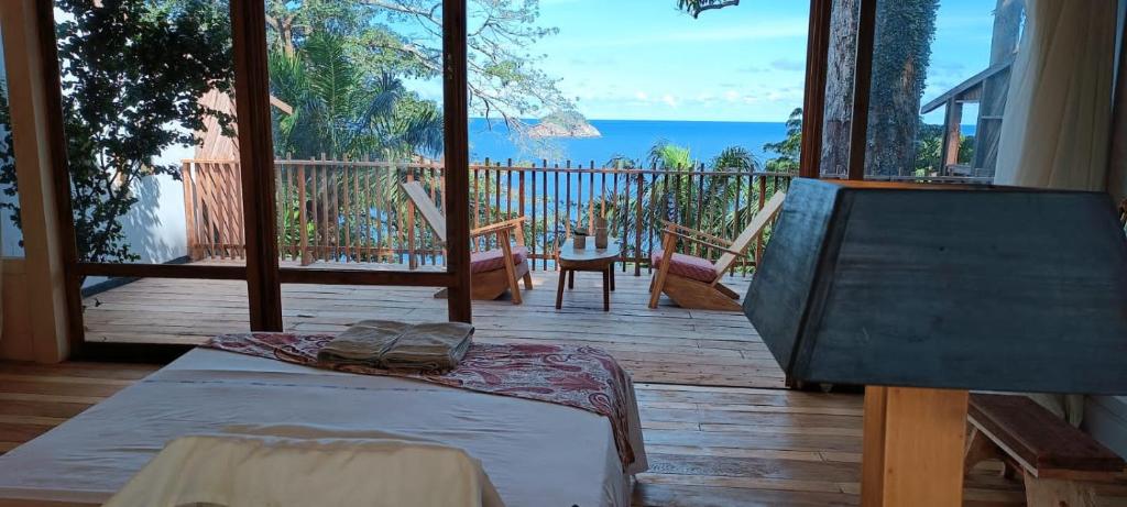 um quarto com uma cama e vista para o oceano em Tribal Green Camp Private Room 1 em SantʼAna
