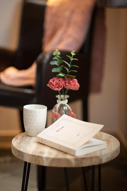 a table with a vase of flowers and a book at Hôtel Grand Confort Le Moulin Rouge in Terrasson-Lavilledieu