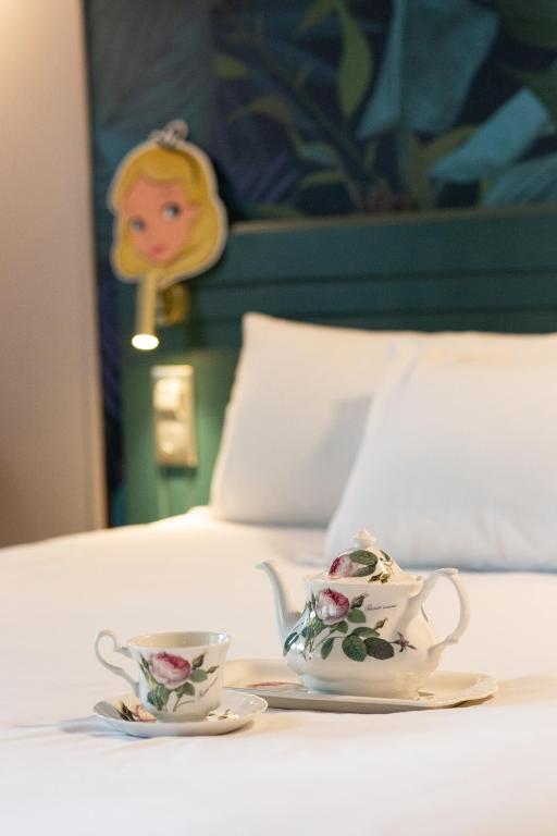 a table with a cup and a tea set on a bed at Hôtel Grand Confort Le Moulin Rouge in Terrasson-Lavilledieu
