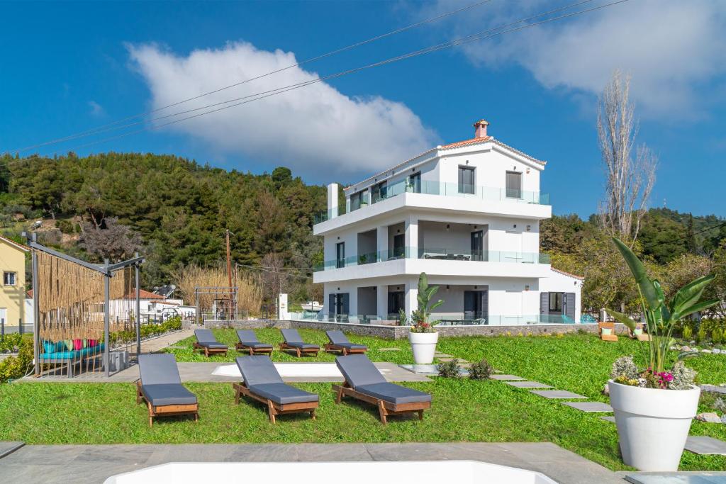 a white house with lounge chairs in front of it at Mythos Luxury Villa-Skiathos in Troulos