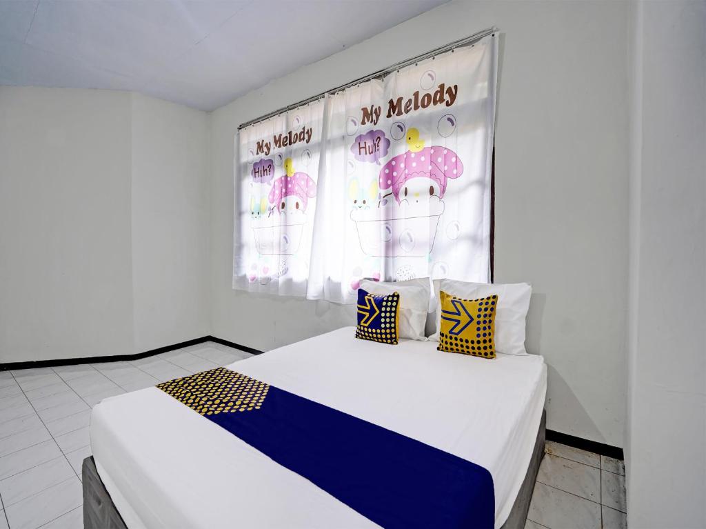 een slaapkamer met een bed met een spandoek aan de muur bij SPOT ON 92388 Villa Segi Delapan in Prigen