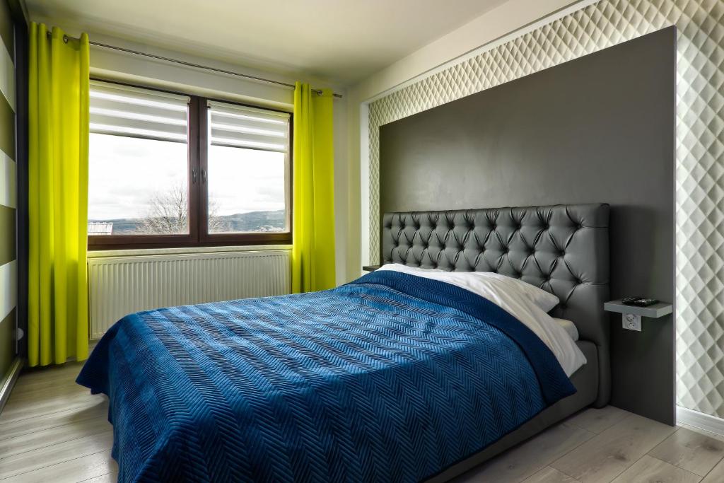 um quarto com uma cama com um edredão azul e uma janela em Apartamenty Wierchówka em Bukowina Tatrzańska