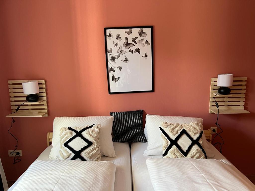 twee bedden in een kamer met oranje muren bij Stylische Gartenwohnung mit Bergblick in Sankt Michael ob Bleiburg