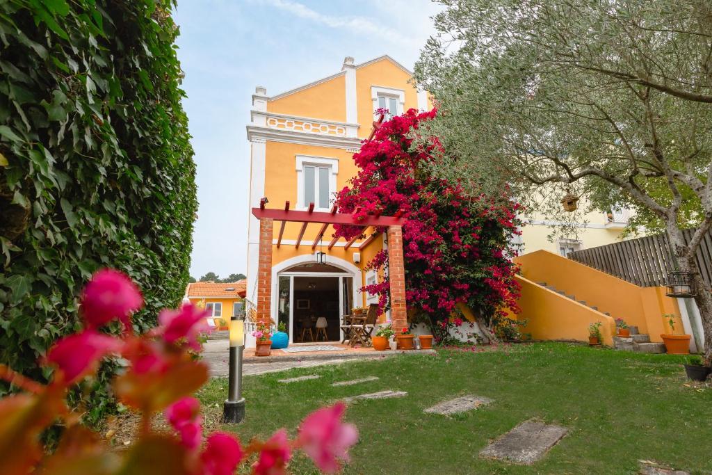 una casa amarilla con flores rojas en el patio en Casa da Foz - Charming House, en Foz do Arelho