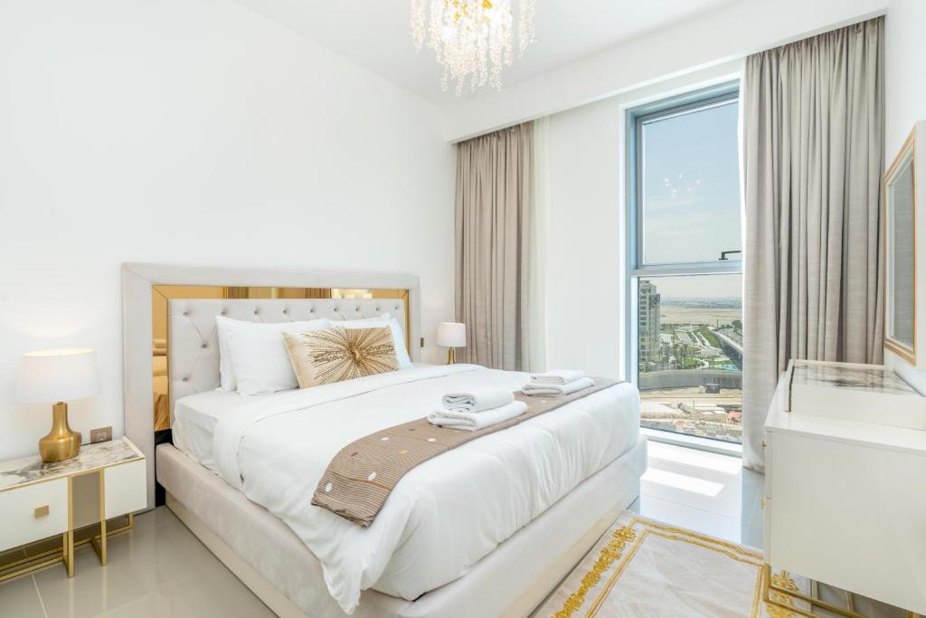 a white bedroom with a large bed and a window at Vacay Lettings - Getaway home Dubai Creek Harbour in Dubai