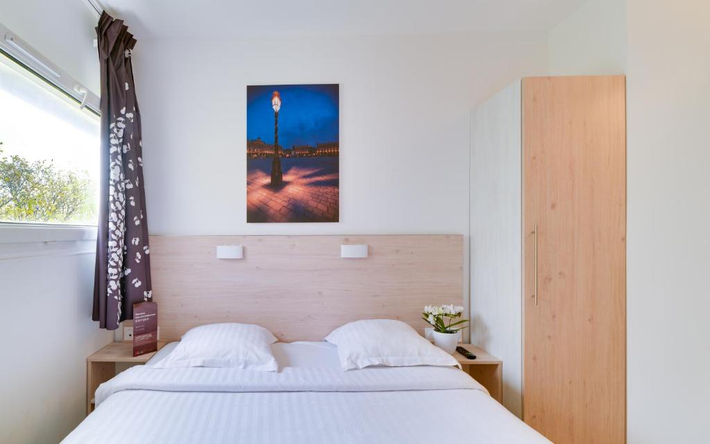 a bedroom with a large white bed and a window at Hotel Cerise Nancy in Nancy