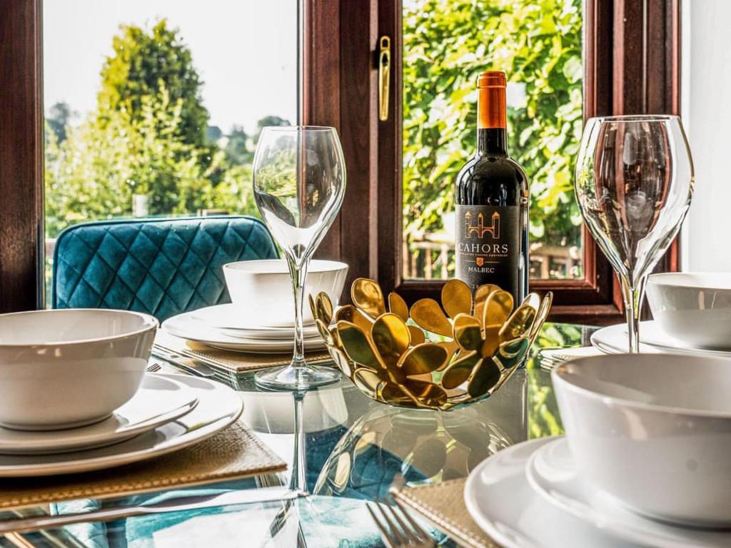 einen Glastisch mit einer Flasche Wein und Gläsern in der Unterkunft Belle Cottage in Ashbourne