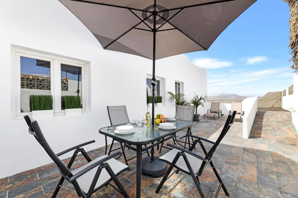 Un patio con una mesa y sillas y una sombrilla. en Home2Book Charming Apartment Teguise, Terrace, en Teguise