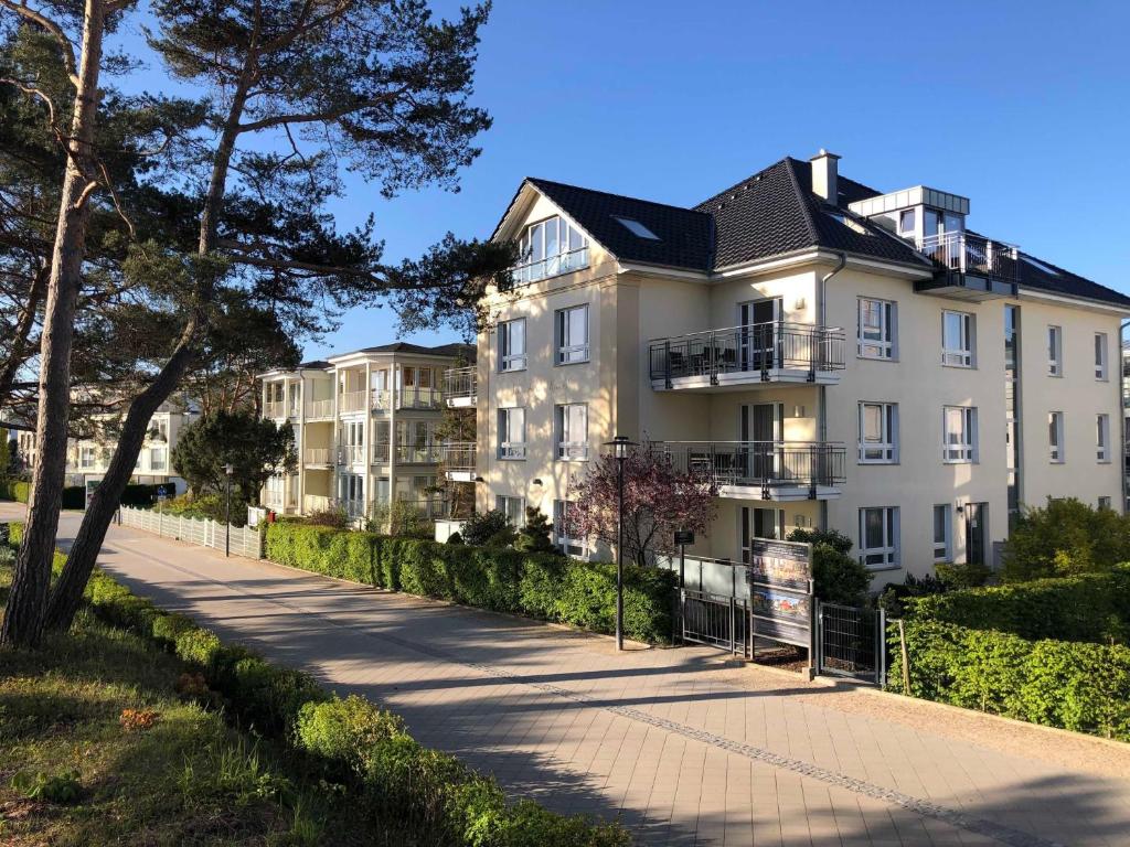 a white building with a black roof on a sidewalk at Strandhaus Aurell in Heringsdorf