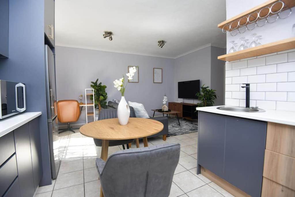 a kitchen with a table and a living room at Comfy Hatfield Appartment in Pretoria