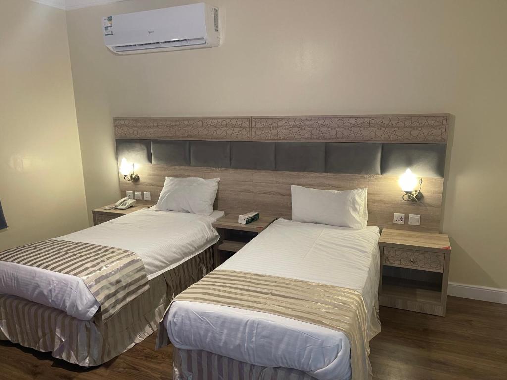 a hotel room with two beds and a desk at فندق نزهة النسيم in Ash Shishah