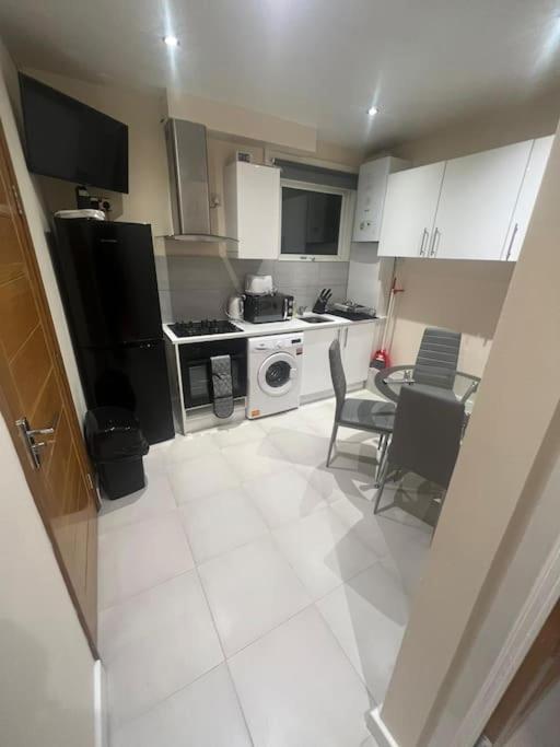 uma cozinha com electrodomésticos pretos e uma mesa e cadeiras em 2 Bedroom Apartment,Chester Road N17 em Londres