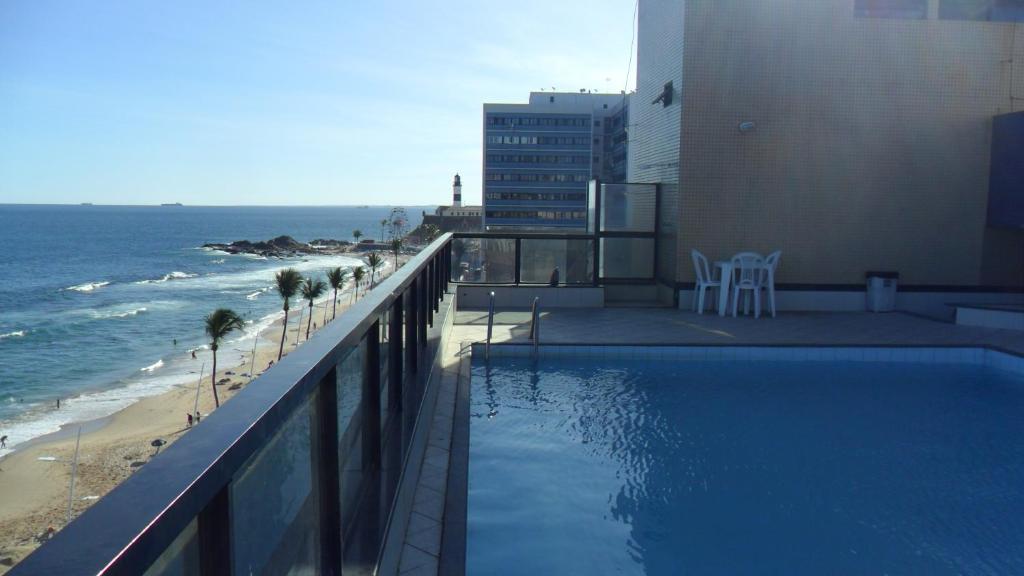 una piscina junto a un edificio y al océano en Farol Barra Flat, en Salvador
