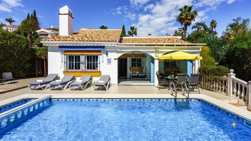 a villa with a swimming pool in front of a house at Villa Caleta Ref 196 in Fuengirola