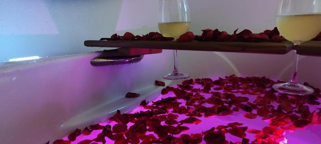 a bathtub filled with red flowers and two glasses of wine at Studio e Suite no Centro de Juquehy a 150mts da praia - Varanda e Serviço de Praia --- E MAIS Ofurô - Cozinha e Estacionamento nas unidades "STUDIO" -- TUDO NOVO in Juquei