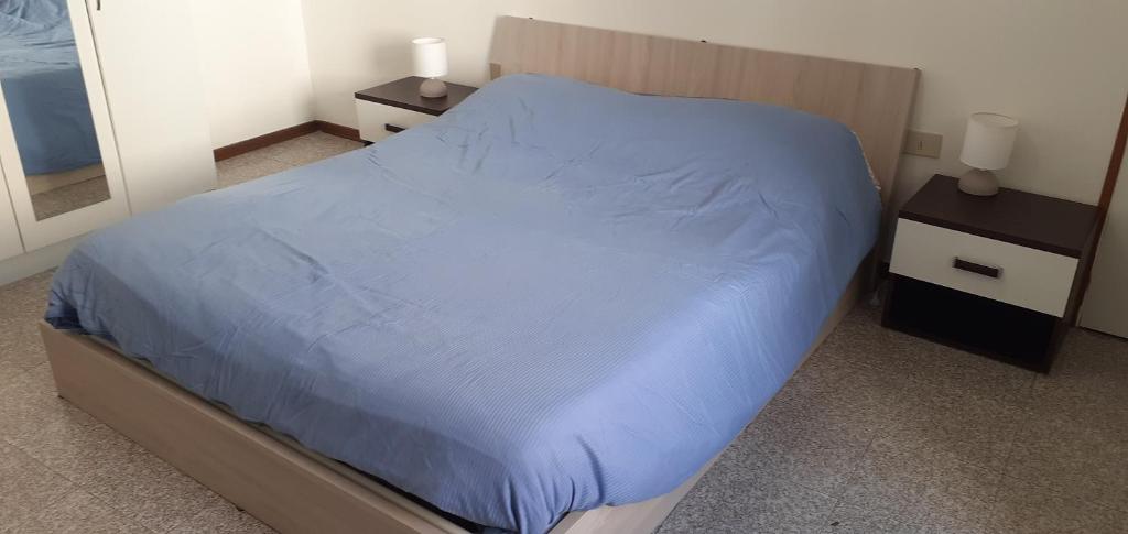 a bedroom with a bed with blue sheets and two night stands at Romiti Apartment in Ferrara