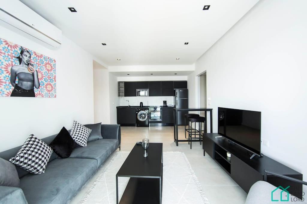 a living room with a couch and a kitchen at Sunset 302 Apt de luxe avec salle de fitness in Tunis