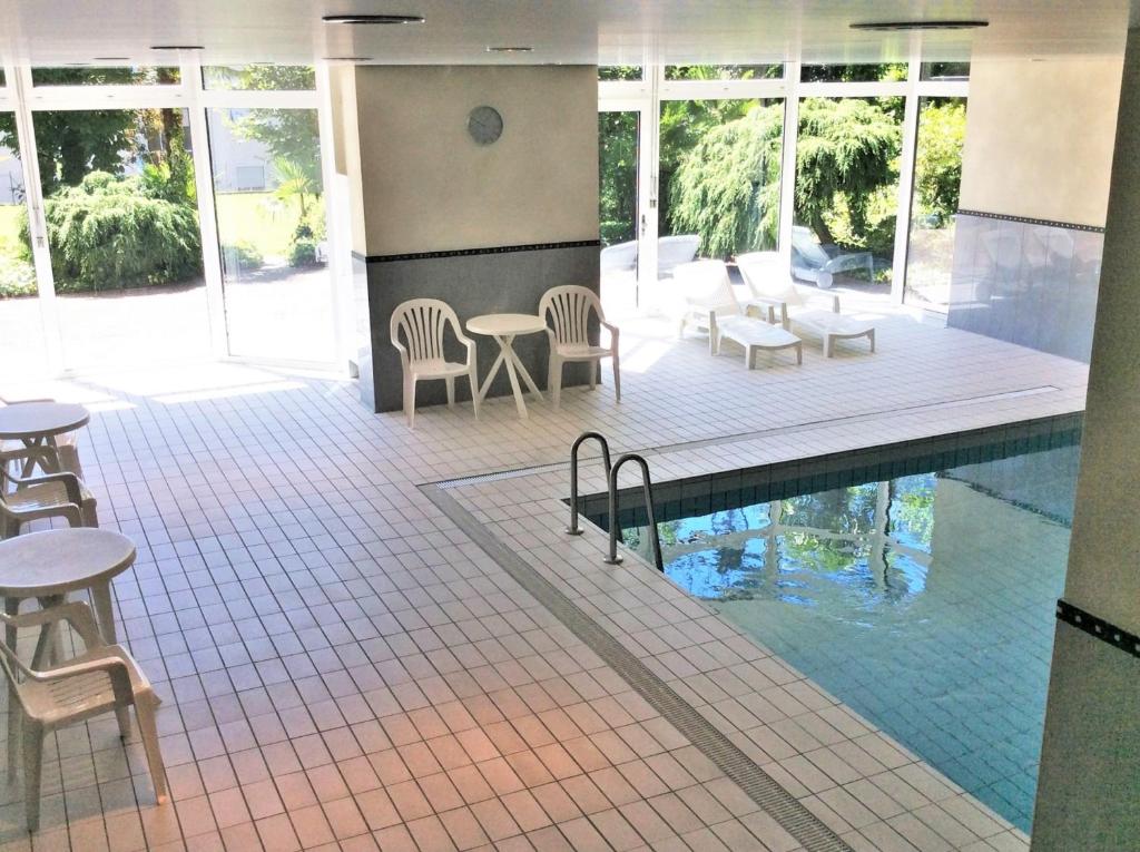 einen Pool in einem Gebäude mit Stühlen und Tischen in der Unterkunft Onyx in Locarno