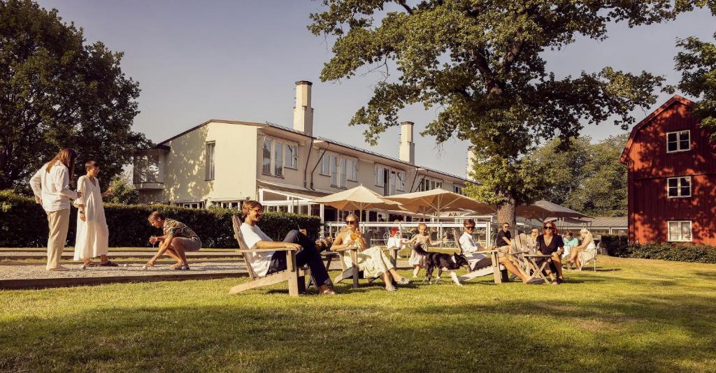 a group of people sitting in the grass in front of a building at Villa Källhagen in Stockholm