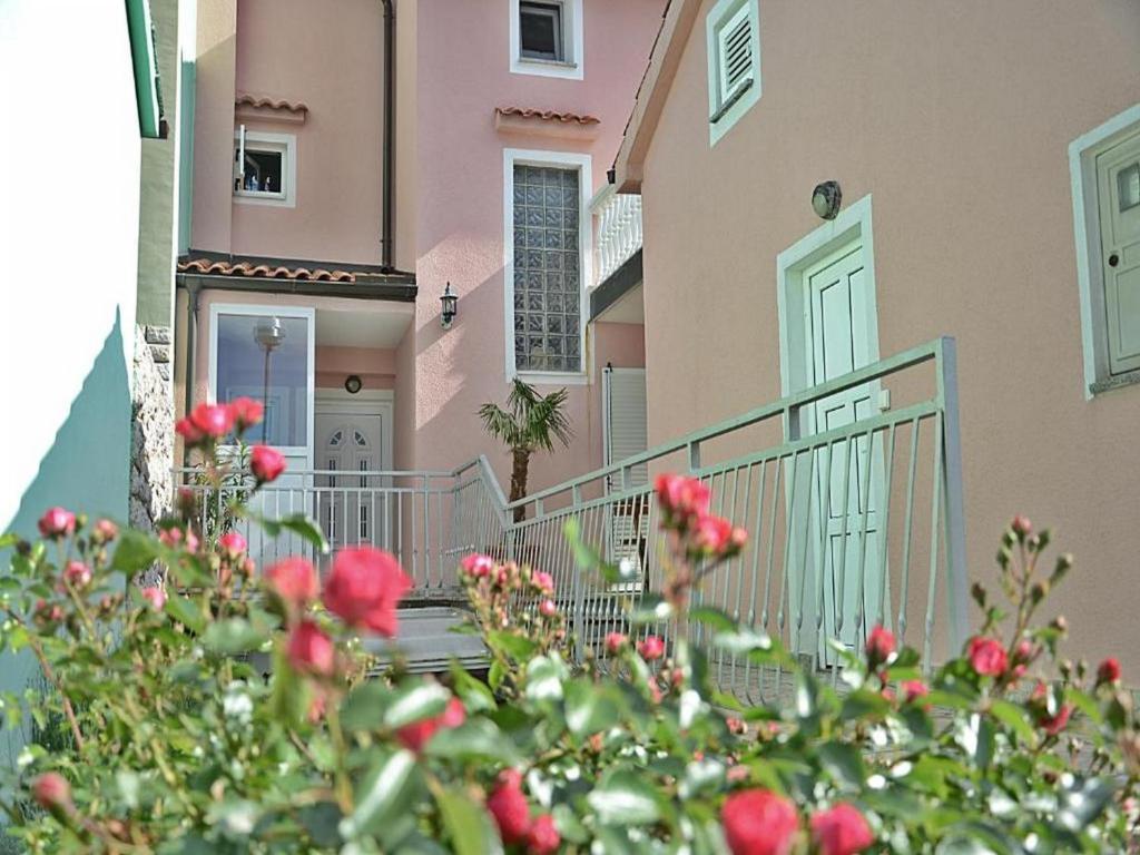 una casa rosa con una puerta y flores delante de ella en Apartment Lucia en Omišalj