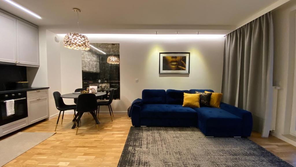 uma sala de estar com um sofá azul e uma mesa em Lenki apartamenty Białołęka em Varósvia