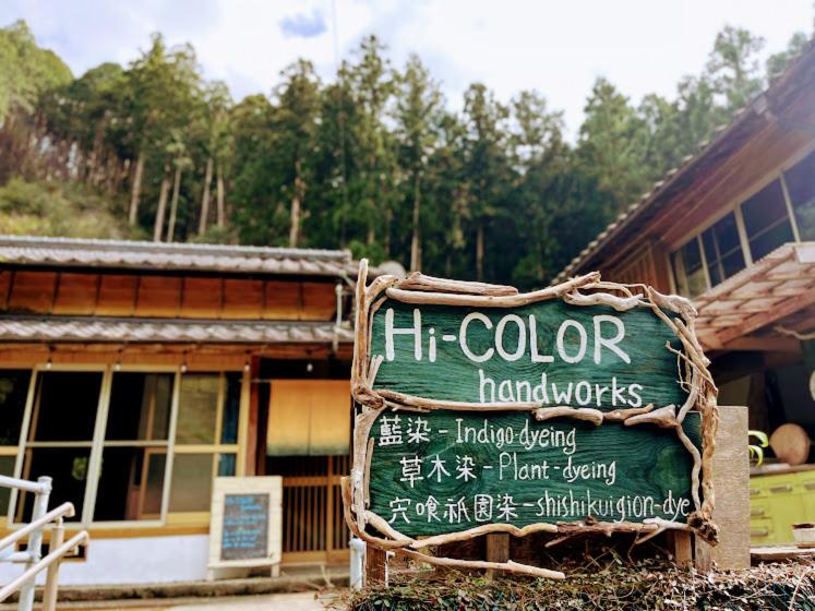 una señal frente a una casa con un edificio en Hi-COLOR handworks, en Hiura