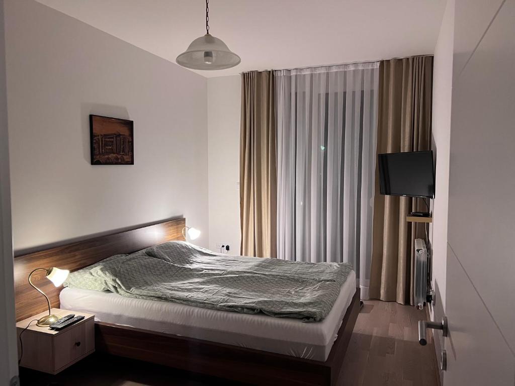 a bedroom with a bed and a window with a television at SkyView Apartment in Sarajevo