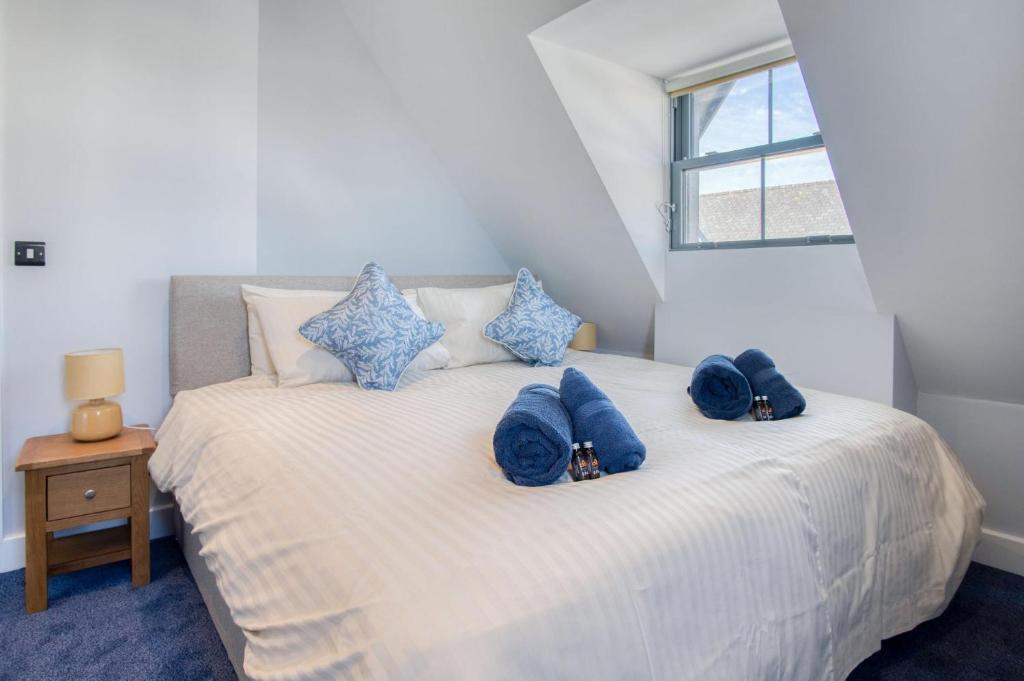 Un dormitorio con una cama con almohadas azules y una ventana en Ocean Cabins No 10 At The Square - Saundersfoot en Saundersfoot