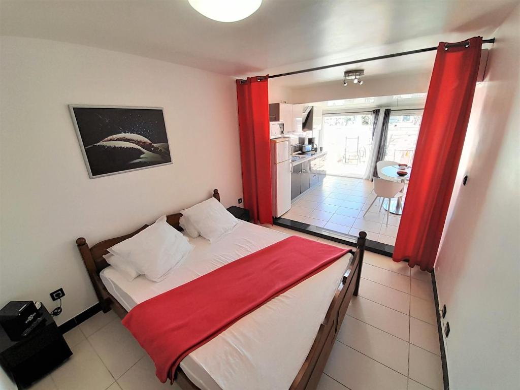 une chambre avec un lit avec un rideau rouge dans l'établissement Studio Village Naturiste Devil or Eden, au Cap d'Agde