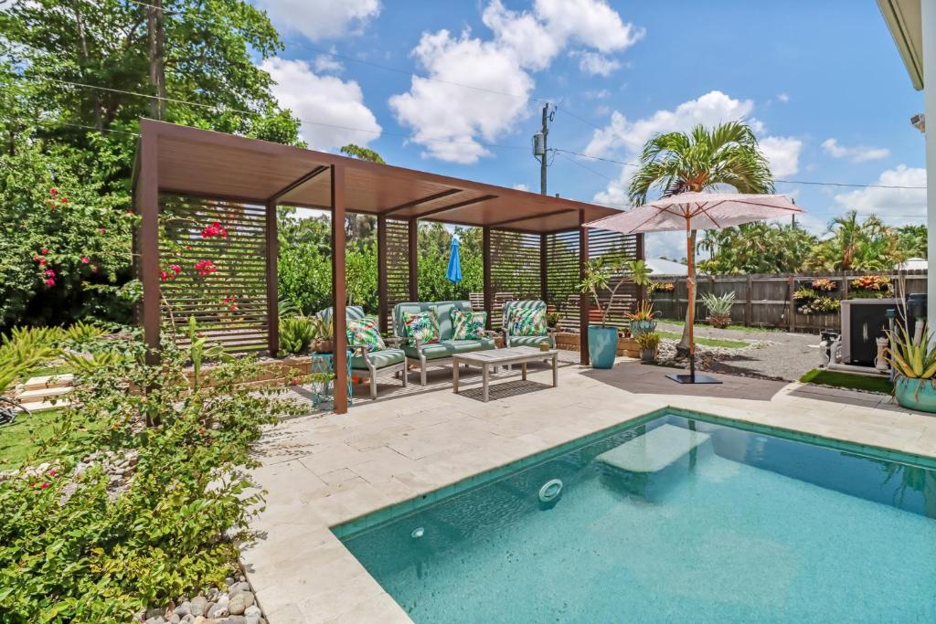 a backyard with a swimming pool and an umbrella at Coastal Soul House in the heart of Naples in Naples